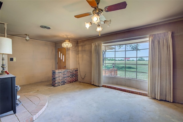 interior space featuring concrete block wall, visible vents, a ceiling fan, unfinished concrete flooring, and a wood stove