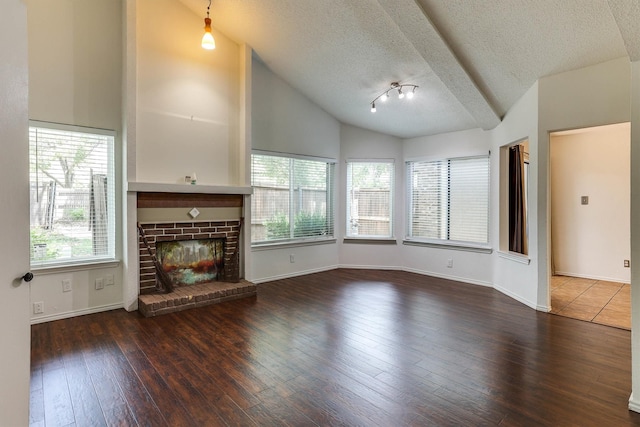 unfurnished living room with hardwood / wood-style flooring, plenty of natural light, vaulted ceiling, and a brick fireplace