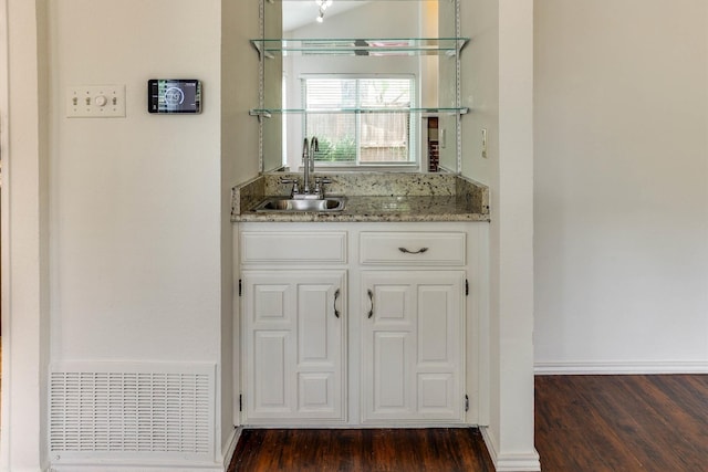 bar featuring white cabinets, dark hardwood / wood-style flooring, stone countertops, and sink