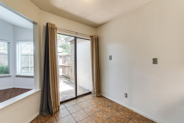 doorway to outside featuring vaulted ceiling, light tile patterned floors, and a textured ceiling