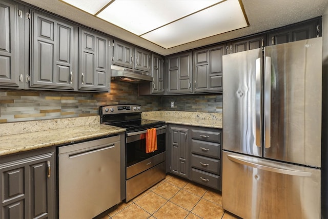 kitchen featuring decorative backsplash, appliances with stainless steel finishes, light stone counters, and light tile patterned flooring