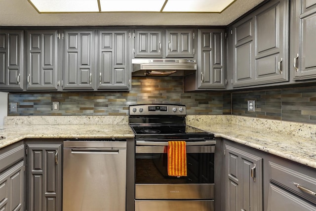 kitchen featuring light stone countertops, backsplash, stainless steel appliances, and gray cabinets