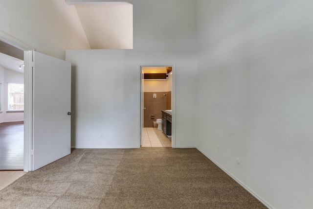 carpeted spare room featuring high vaulted ceiling