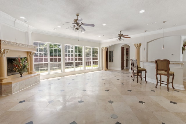 interior space with ceiling fan, a textured ceiling, and ornamental molding