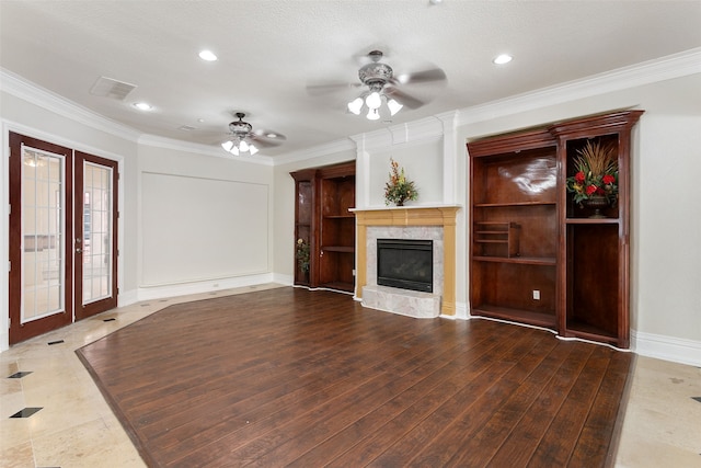 unfurnished living room with a premium fireplace, hardwood / wood-style floors, ceiling fan, and french doors