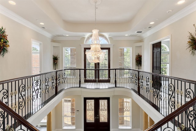 interior space featuring a high ceiling, crown molding, a raised ceiling, and an inviting chandelier