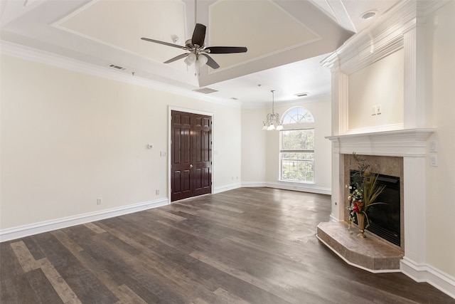 unfurnished living room featuring ornamental molding, ceiling fan with notable chandelier, dark hardwood / wood-style floors, a premium fireplace, and a raised ceiling