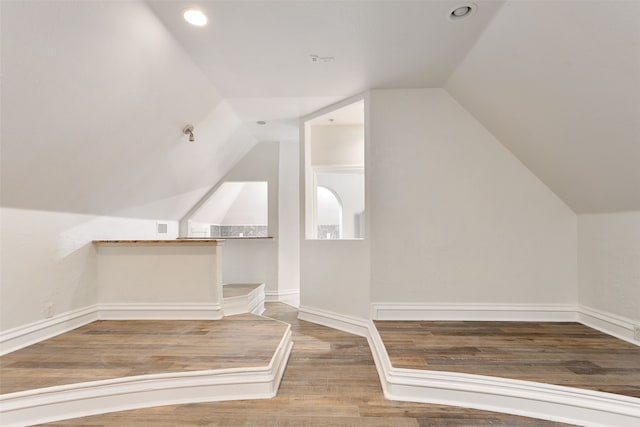 additional living space featuring vaulted ceiling and hardwood / wood-style floors