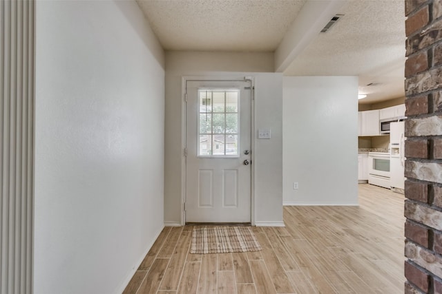 doorway featuring a textured ceiling and light hardwood / wood-style floors