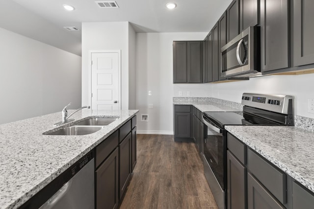 kitchen featuring sink, light stone counters, dark hardwood / wood-style flooring, and appliances with stainless steel finishes