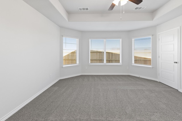 empty room featuring ceiling fan, a tray ceiling, and carpet flooring