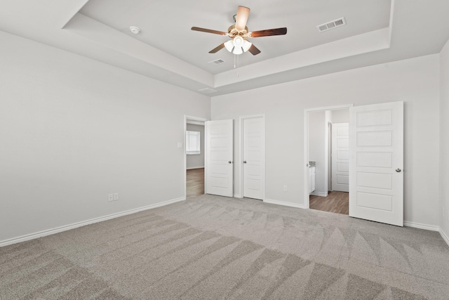 unfurnished bedroom featuring carpet floors, a raised ceiling, and baseboards