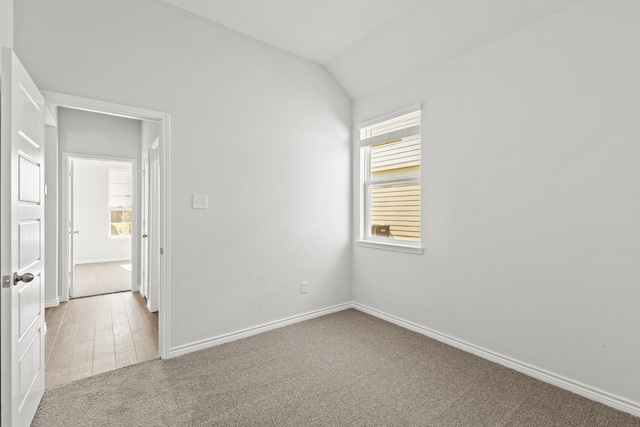 empty room with light carpet, baseboards, and lofted ceiling