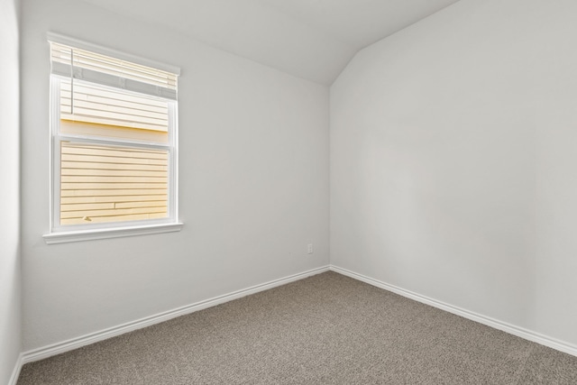 carpeted spare room with lofted ceiling and baseboards