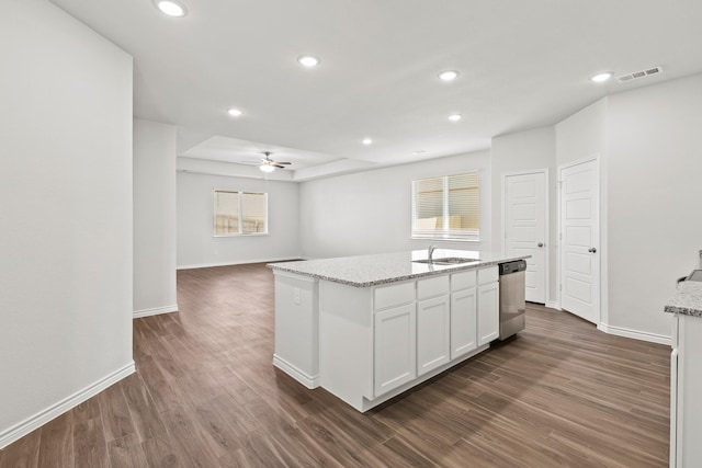 kitchen with a kitchen island with sink, dark wood-style flooring, white cabinetry, stainless steel dishwasher, and light stone countertops