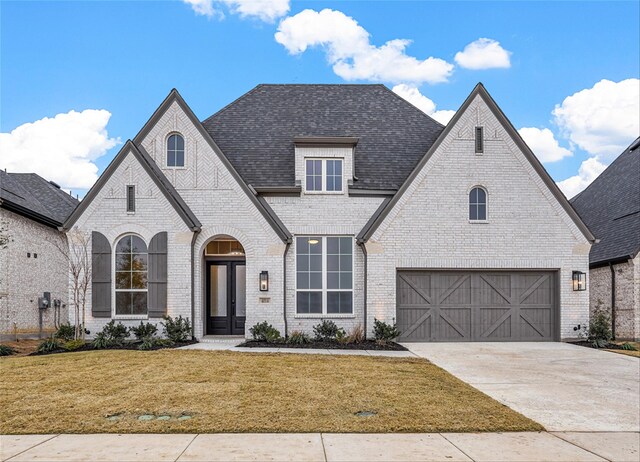 french country home featuring a garage, a front lawn, and french doors