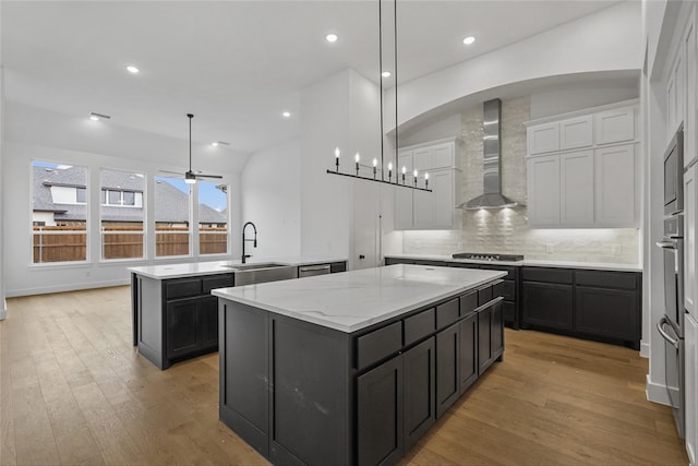 kitchen featuring decorative light fixtures, a center island, and wall chimney exhaust hood