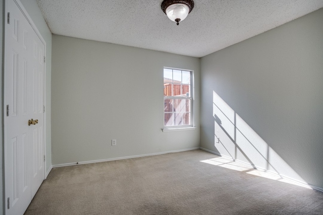 carpeted empty room featuring a textured ceiling