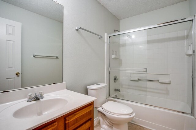 full bathroom featuring toilet, tile floors, bath / shower combo with glass door, vanity, and a textured ceiling