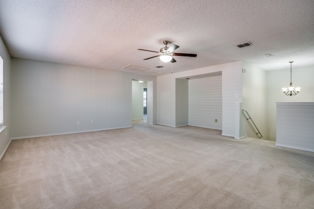 carpeted empty room featuring a textured ceiling and ceiling fan with notable chandelier