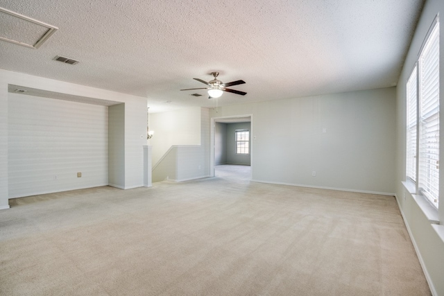 empty room featuring ceiling fan, a textured ceiling, and light carpet