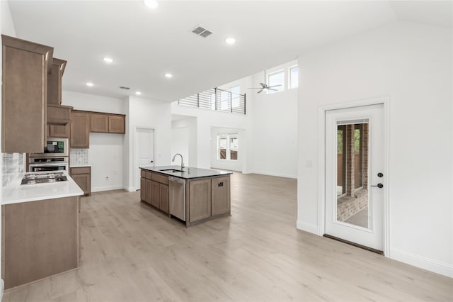 kitchen featuring an island with sink, ceiling fan, sink, light hardwood / wood-style flooring, and appliances with stainless steel finishes