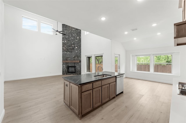 kitchen with a kitchen island with sink, sink, a fireplace, light hardwood / wood-style flooring, and dishwasher