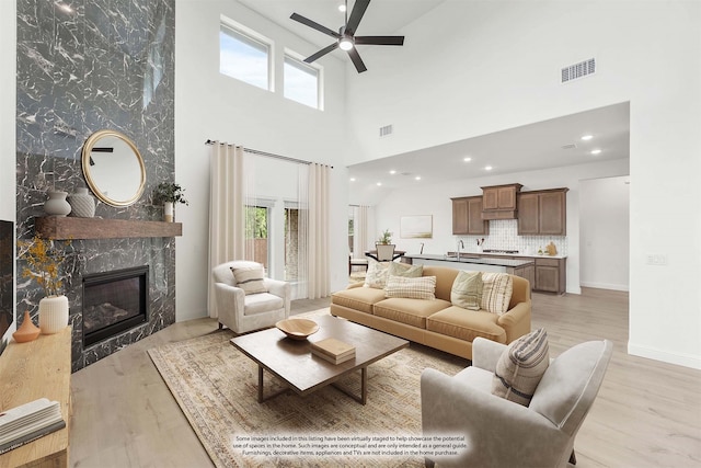 living room featuring light hardwood / wood-style floors, a high ceiling, and a healthy amount of sunlight