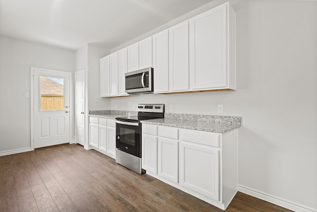 kitchen with dark hardwood / wood-style flooring, white cabinetry, light stone counters, and appliances with stainless steel finishes