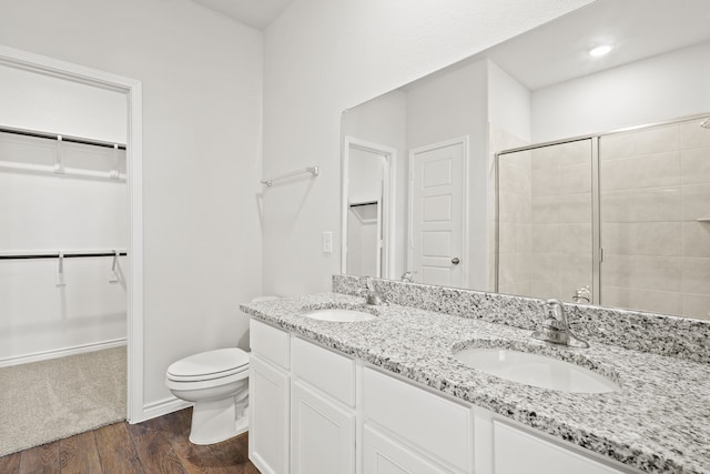 bathroom with hardwood / wood-style flooring, vanity, toilet, and a shower with door