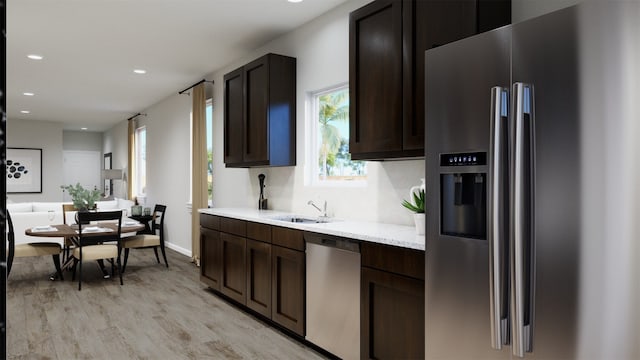 kitchen featuring sink, appliances with stainless steel finishes, dark brown cabinets, light hardwood / wood-style floors, and light stone counters