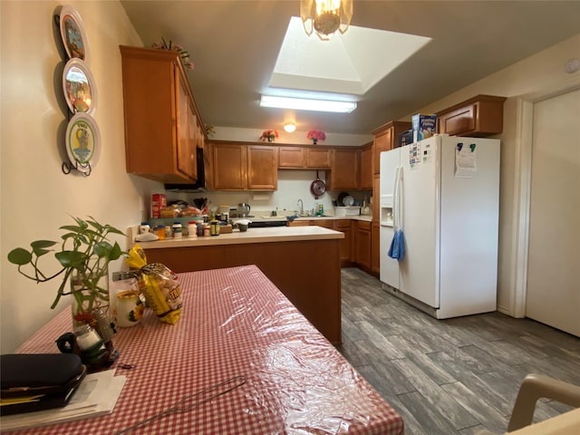 kitchen featuring kitchen peninsula, sink, dark hardwood / wood-style floors, and white refrigerator with ice dispenser