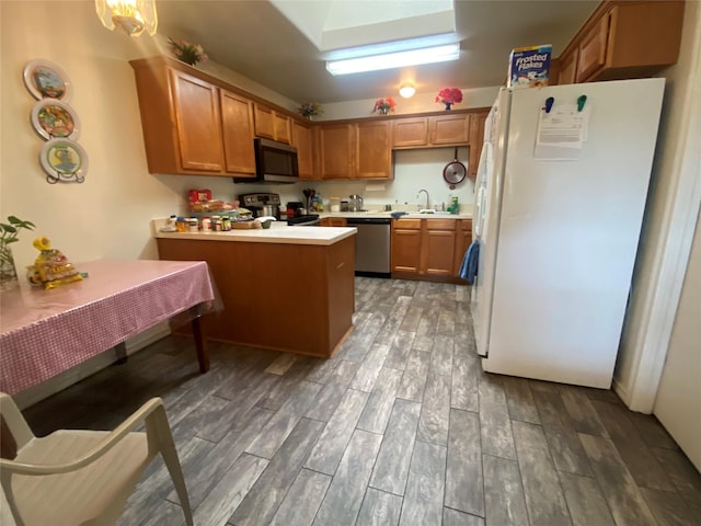 kitchen featuring kitchen peninsula, appliances with stainless steel finishes, dark wood-type flooring, and sink