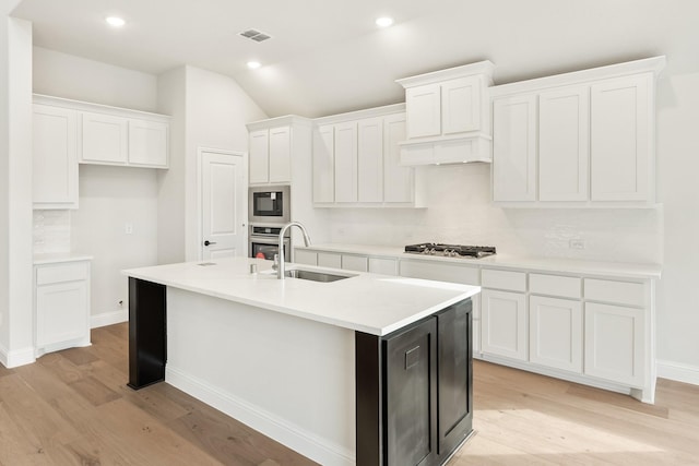 kitchen with a center island with sink, sink, light wood-type flooring, white cabinetry, and stainless steel appliances