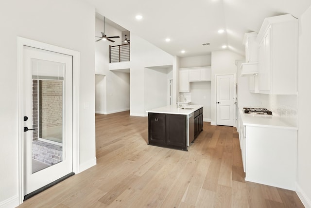 kitchen with ceiling fan, sink, stainless steel gas cooktop, a kitchen island with sink, and dark brown cabinets