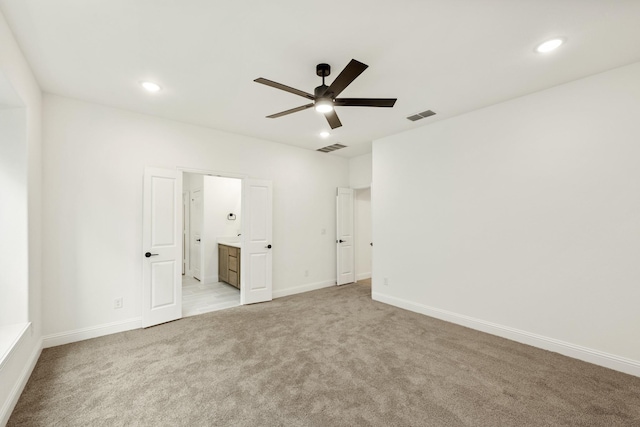 unfurnished bedroom with connected bathroom, light colored carpet, and ceiling fan