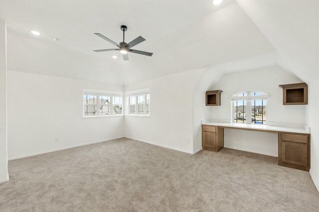 interior space with a wealth of natural light, ceiling fan, light colored carpet, and lofted ceiling