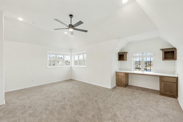 interior space with lofted ceiling, built in desk, light carpet, and ceiling fan