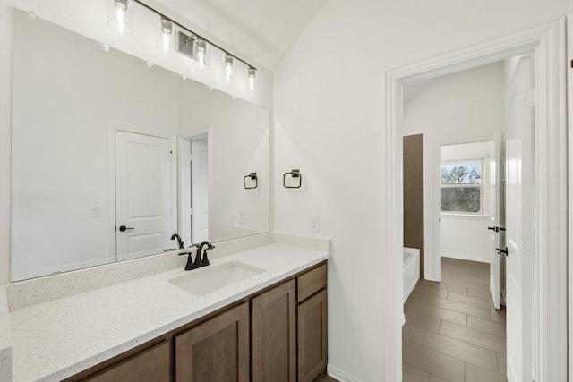 bathroom with shower / bathtub combination, vanity, and vaulted ceiling