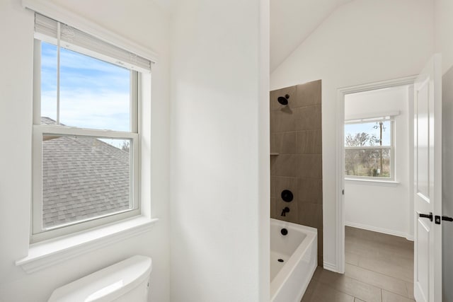 bathroom featuring vaulted ceiling, tile patterned floors, tiled shower / bath combo, and toilet