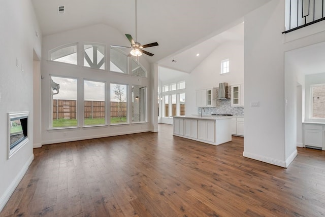 unfurnished living room with visible vents, a ceiling fan, dark wood-type flooring, high vaulted ceiling, and a sink