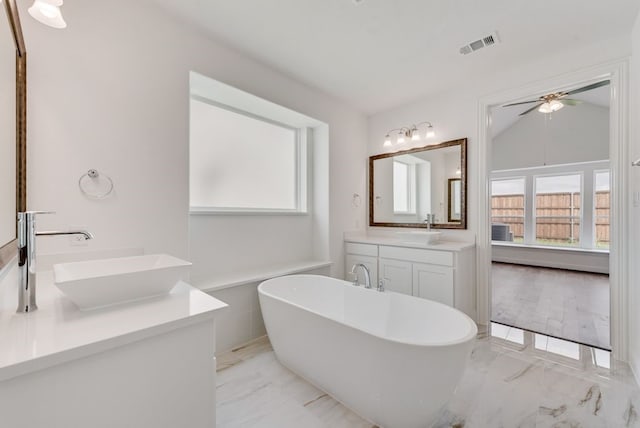 bathroom featuring vaulted ceiling, ceiling fan, a bathtub, and vanity