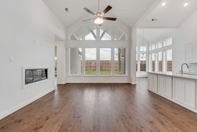 unfurnished living room with ceiling fan, dark hardwood / wood-style flooring, high vaulted ceiling, and sink