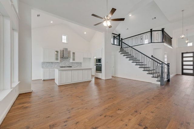 unfurnished living room featuring high vaulted ceiling, hardwood / wood-style floors, and ceiling fan