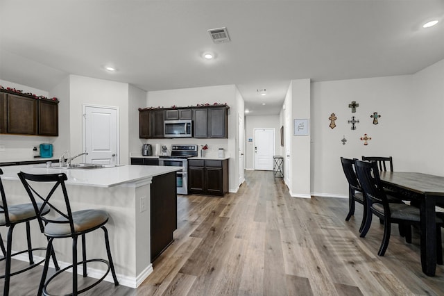 kitchen featuring a center island with sink, dark brown cabinets, sink, and appliances with stainless steel finishes