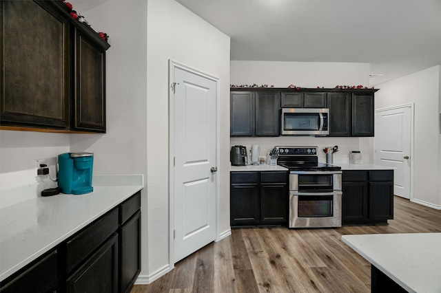 kitchen featuring dark brown cabinets, light hardwood / wood-style floors, and appliances with stainless steel finishes