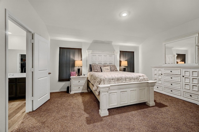 bedroom featuring dark colored carpet, ensuite bathroom, and sink