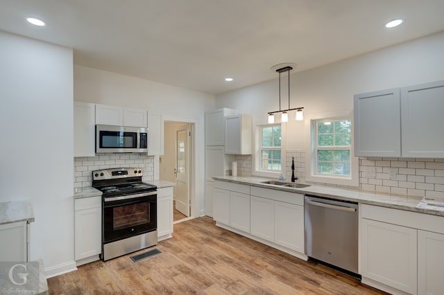 kitchen with sink, decorative light fixtures, white cabinets, and appliances with stainless steel finishes