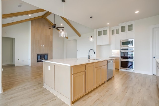 kitchen featuring a fireplace, appliances with stainless steel finishes, an island with sink, sink, and ceiling fan