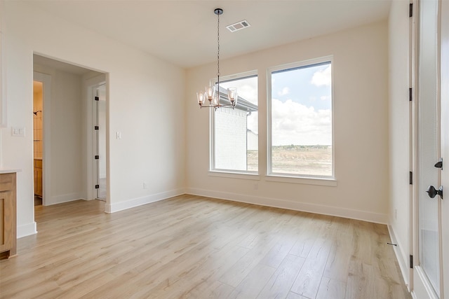 unfurnished dining area with an inviting chandelier and light hardwood / wood-style floors